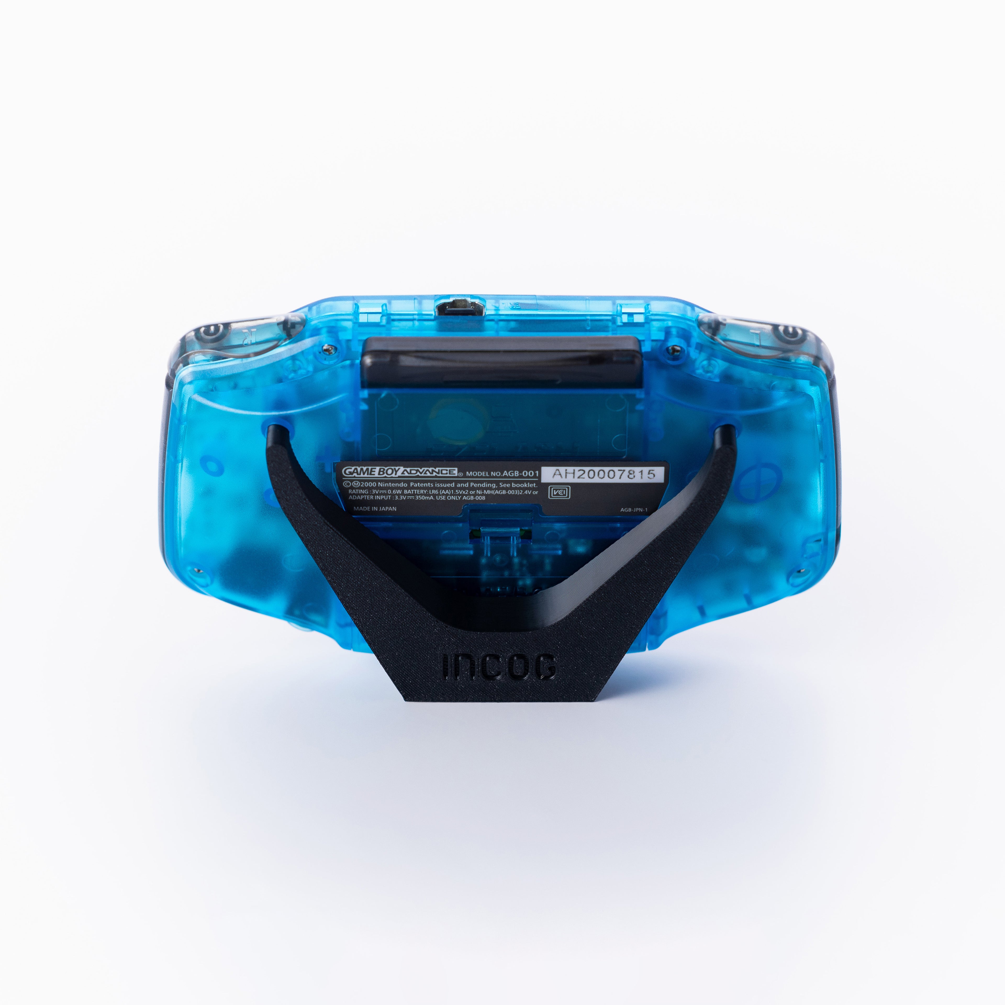 A translucent blue gameboy advance with a black INCOG display stand, photographed from the back on a clean off white background.