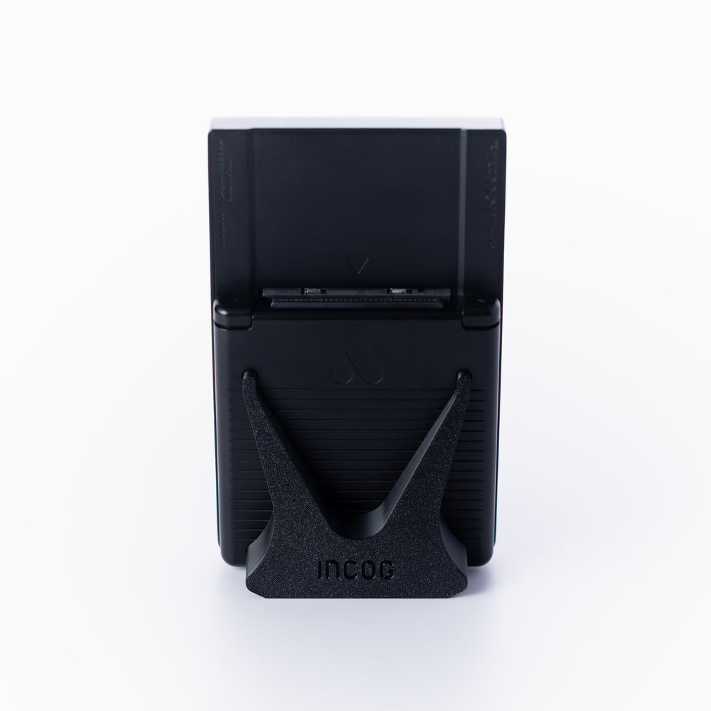 A black Analogue Pocket console using an INCOG display stand shown from the rear, against a clean off white background.