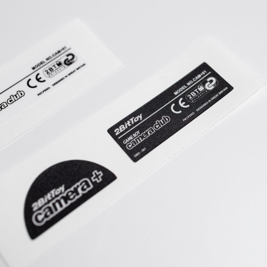 Close-up of a 2BitToy camera+ black vinyl label on a white background
