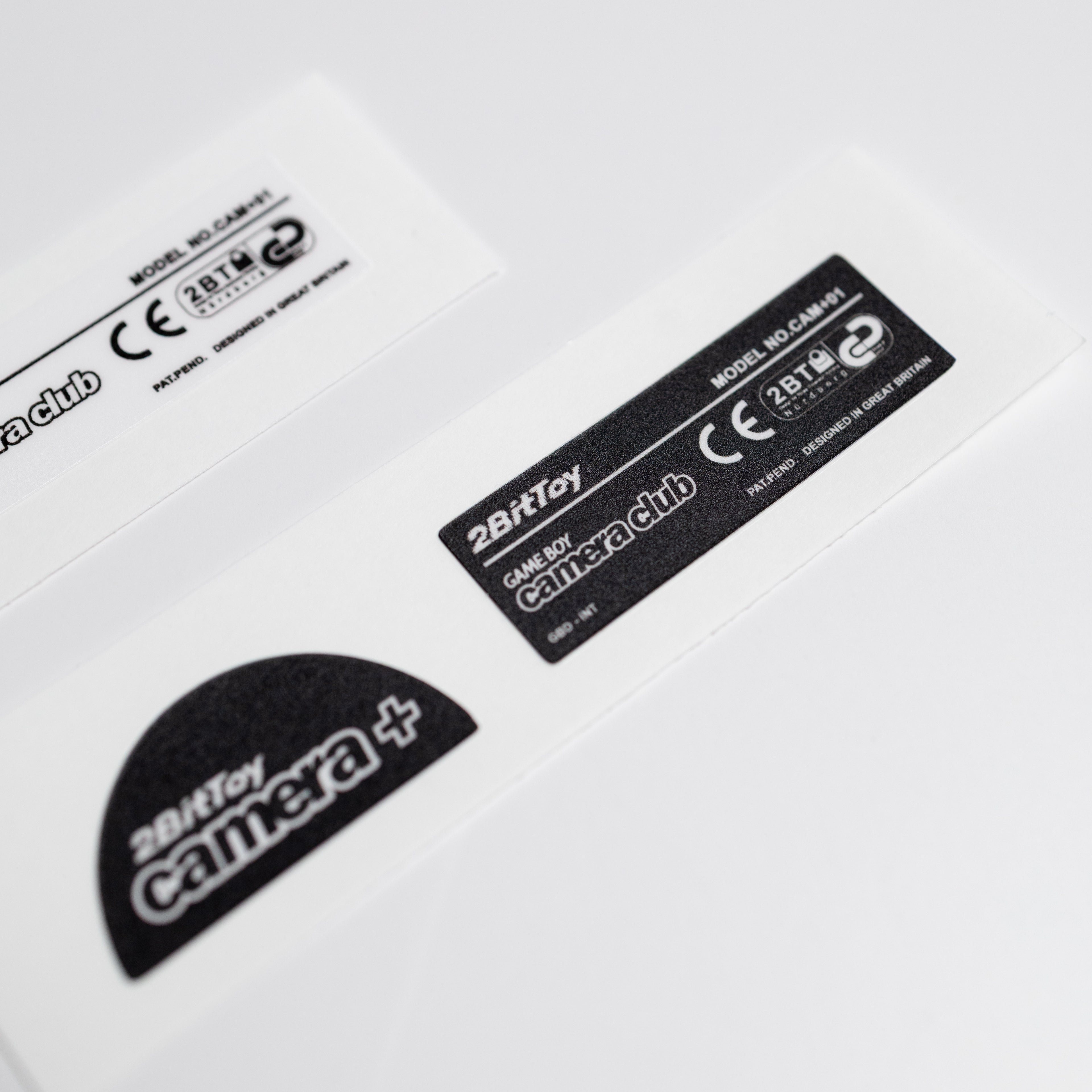 Close-up of a 2BitToy camera+ black vinyl label on a white background