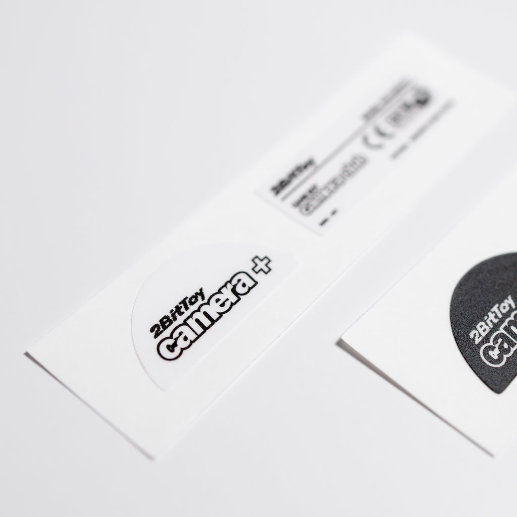 Close-up of a 2BitToy camera+ white vinyl label on a white background