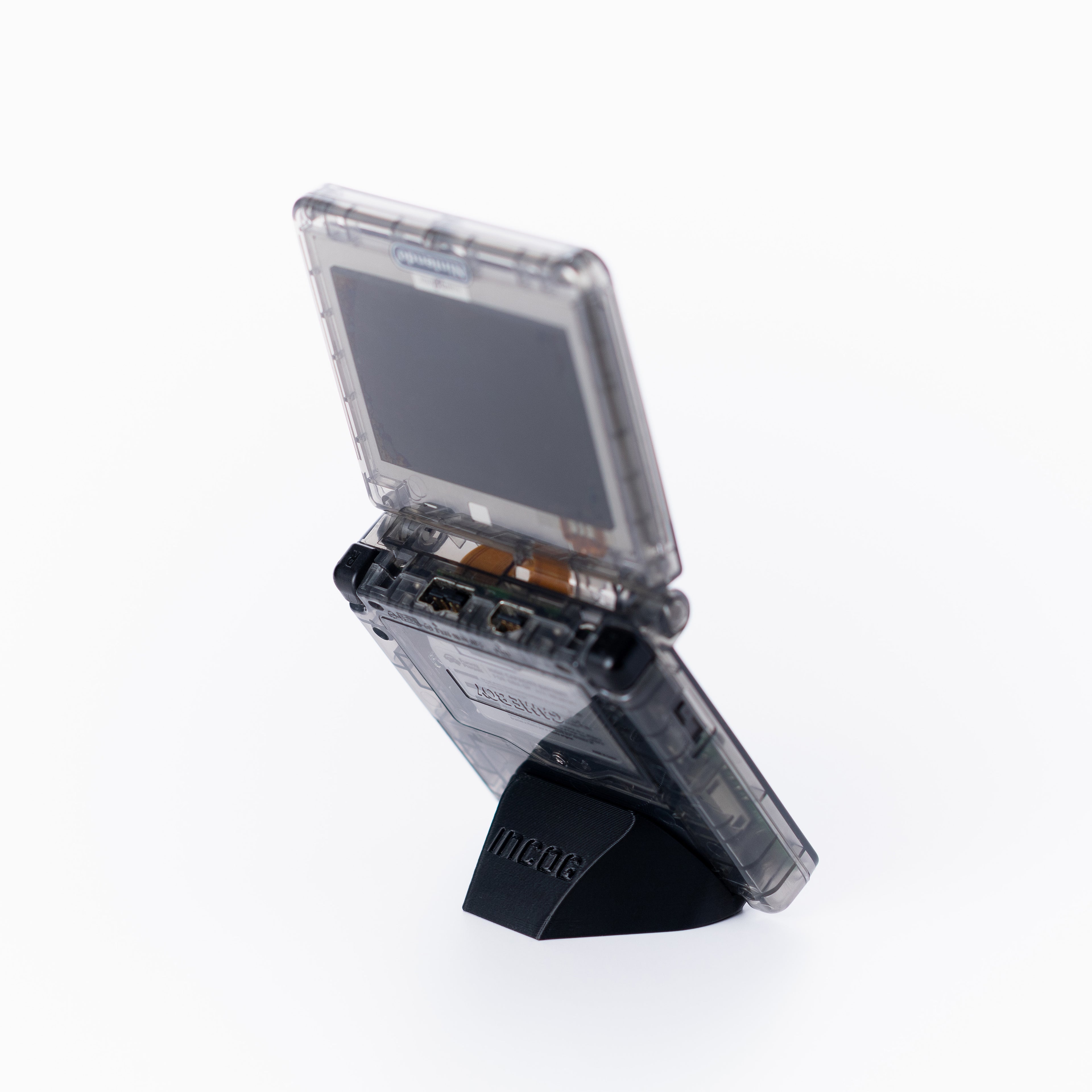 A translucent black game boy advance sp console standing open on a black INCOG display stand, photographed against a clean off white background.