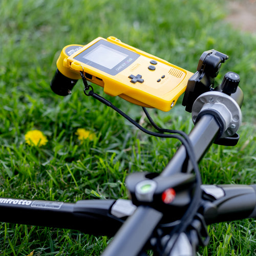 A sturdy yellow Cradle holding a Game Boy Color steady on a tripod, demonstrating the hands-free macro photography capabilities of the Tripod Edition.