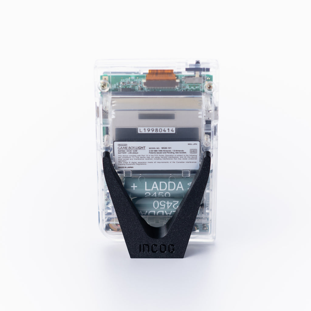 Rear view of a transparent Game Boy light, using an INCOG display stand, set against a plain off white background.