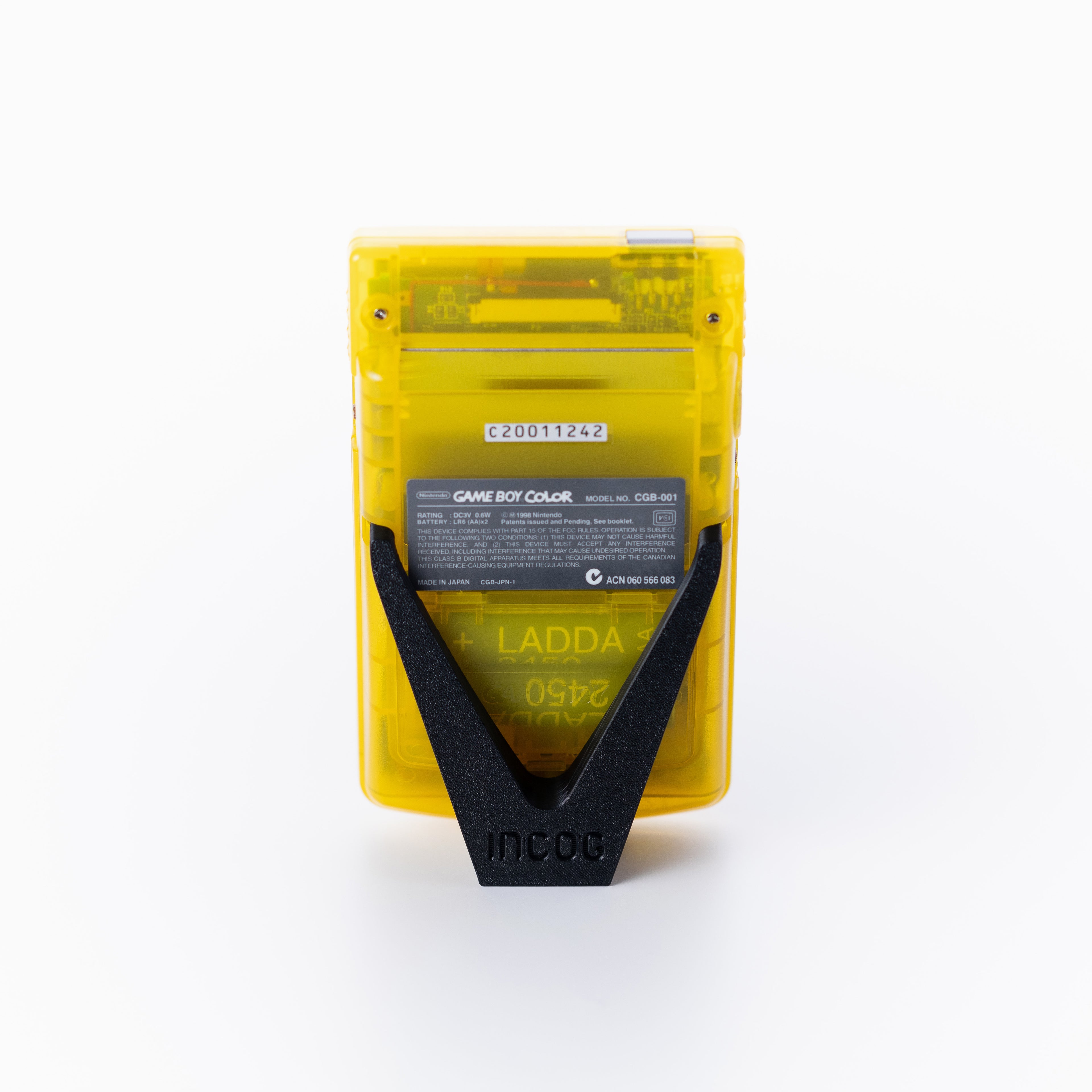 A translucent yellow Game Boy Color shown from the back using an INCOG display stand on an off white background.
